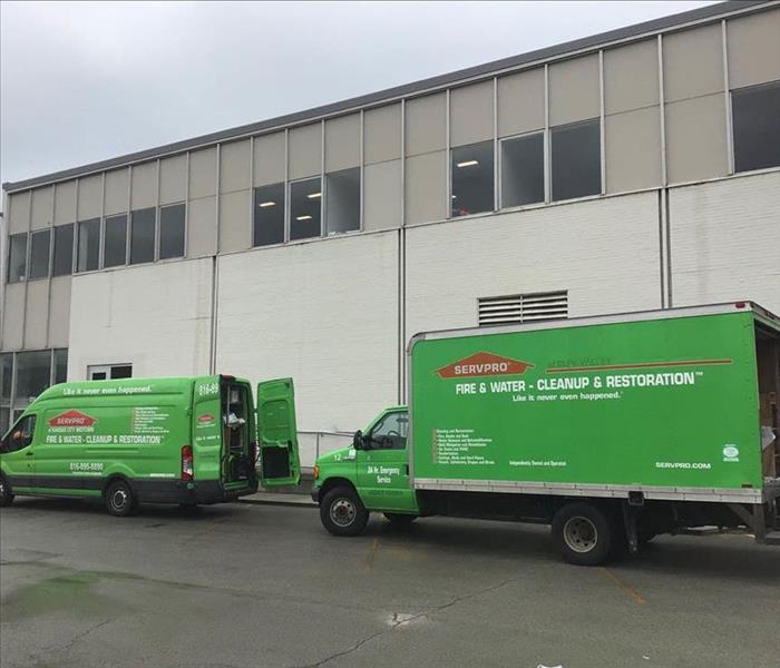 Two SERVPRO vans parked outside a job site. 
